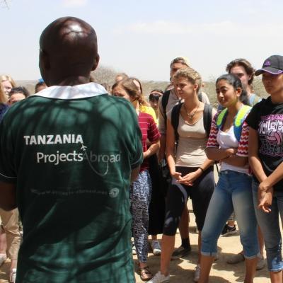 A group of Projects Abroad Culture and Community Volunteers are being briefed about Maasai culture during Cultural Immersion in Tanzania. A group of Community volunteers are outside being taught about Maasai Culture during their Community volunteer work in Tanzania.